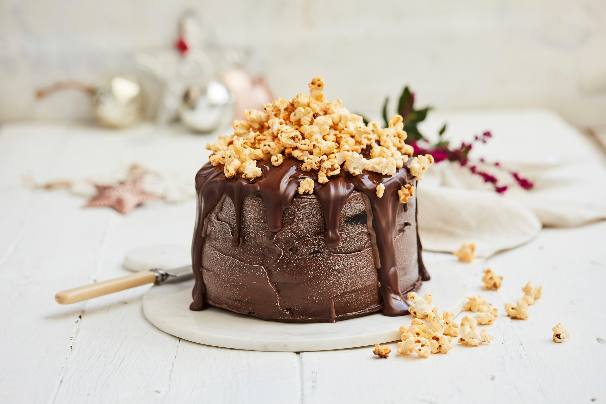 Advertising location photography for IGA of a chocolate cake dripping in chocolate icing covered in popcorn