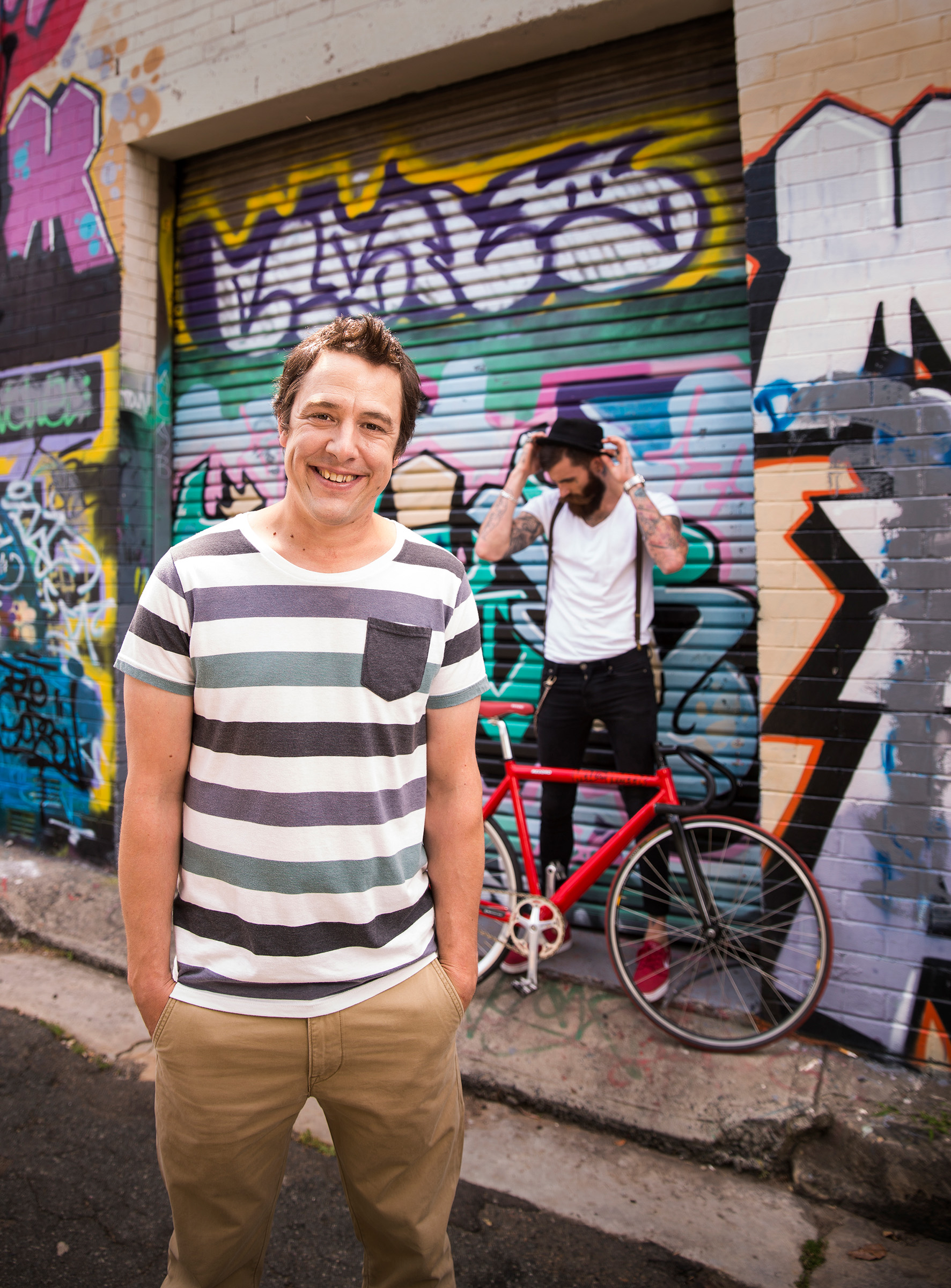 Advertising Editorial photo photography of Samuel Johnson for SBS TV series Hipster in laneway with graffiti and hipster with red bike