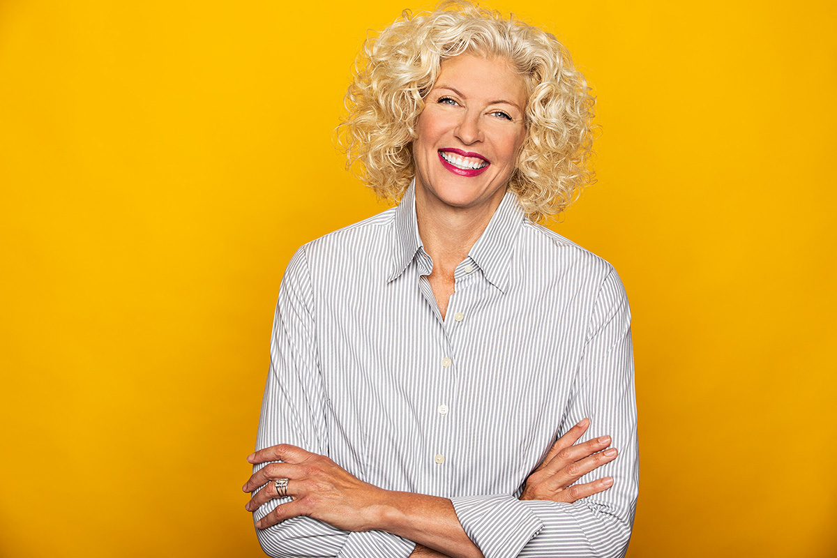 Studio portrait photography of smiling female Kim Skildum-Reid on yellow background