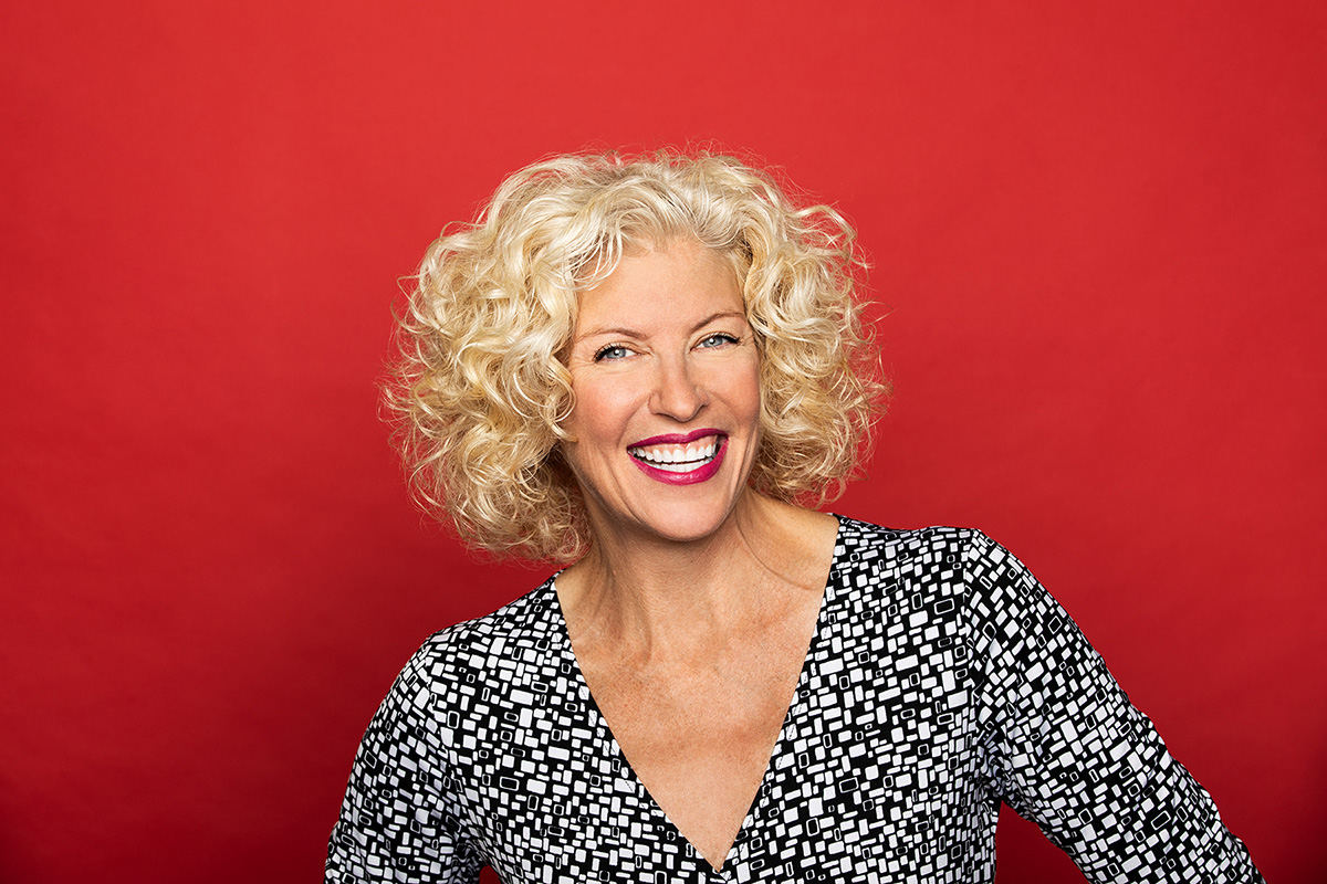 Studio portrait photography of smiling female Kim Skildum-Reid on red background