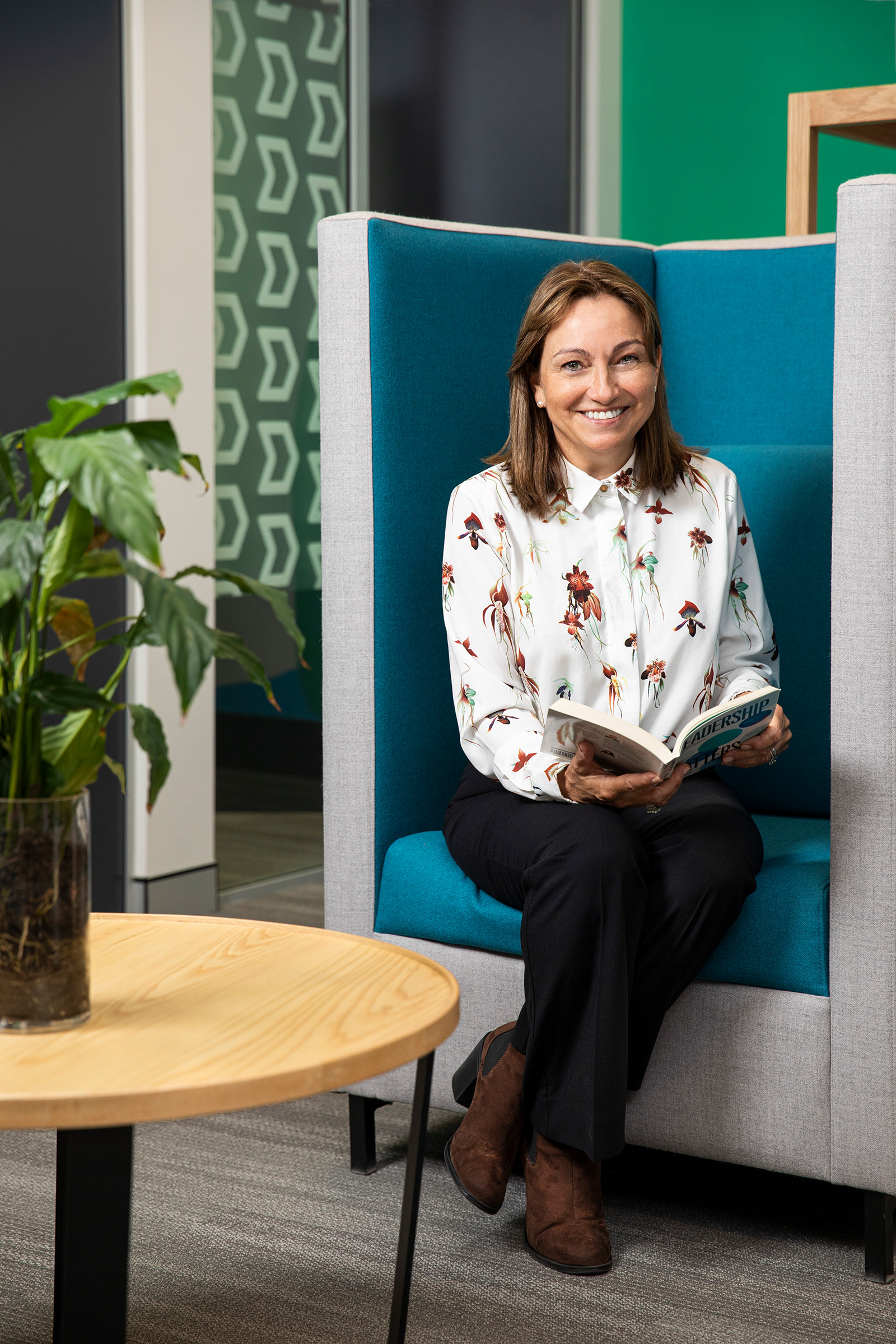 Corporate environmental corporate photography of smiling female sitting in reception area reading a book