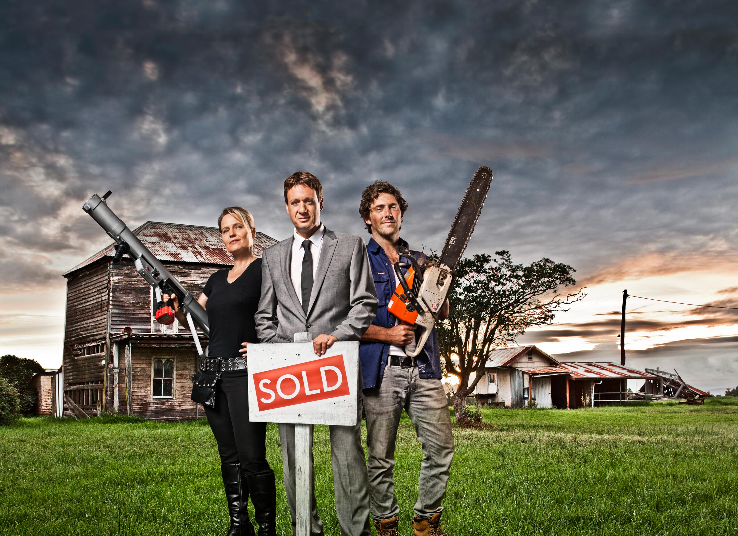Advertising photography Selling Houses Shaynna holding power tool Andrew SOLD sign Charlie holding chainsaw by old house