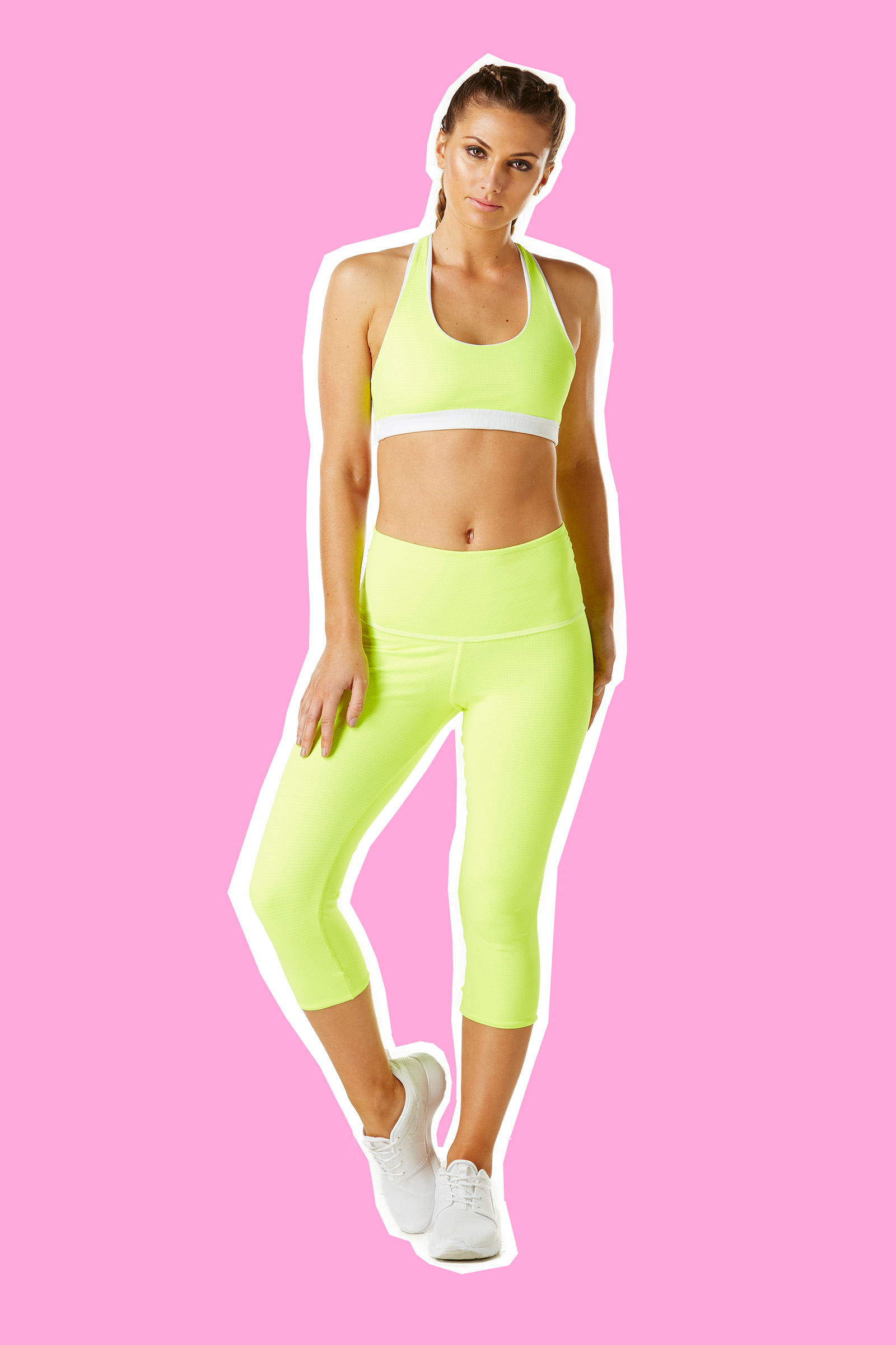 Studio fashion photography of female model wearing yellow activewear on pink background