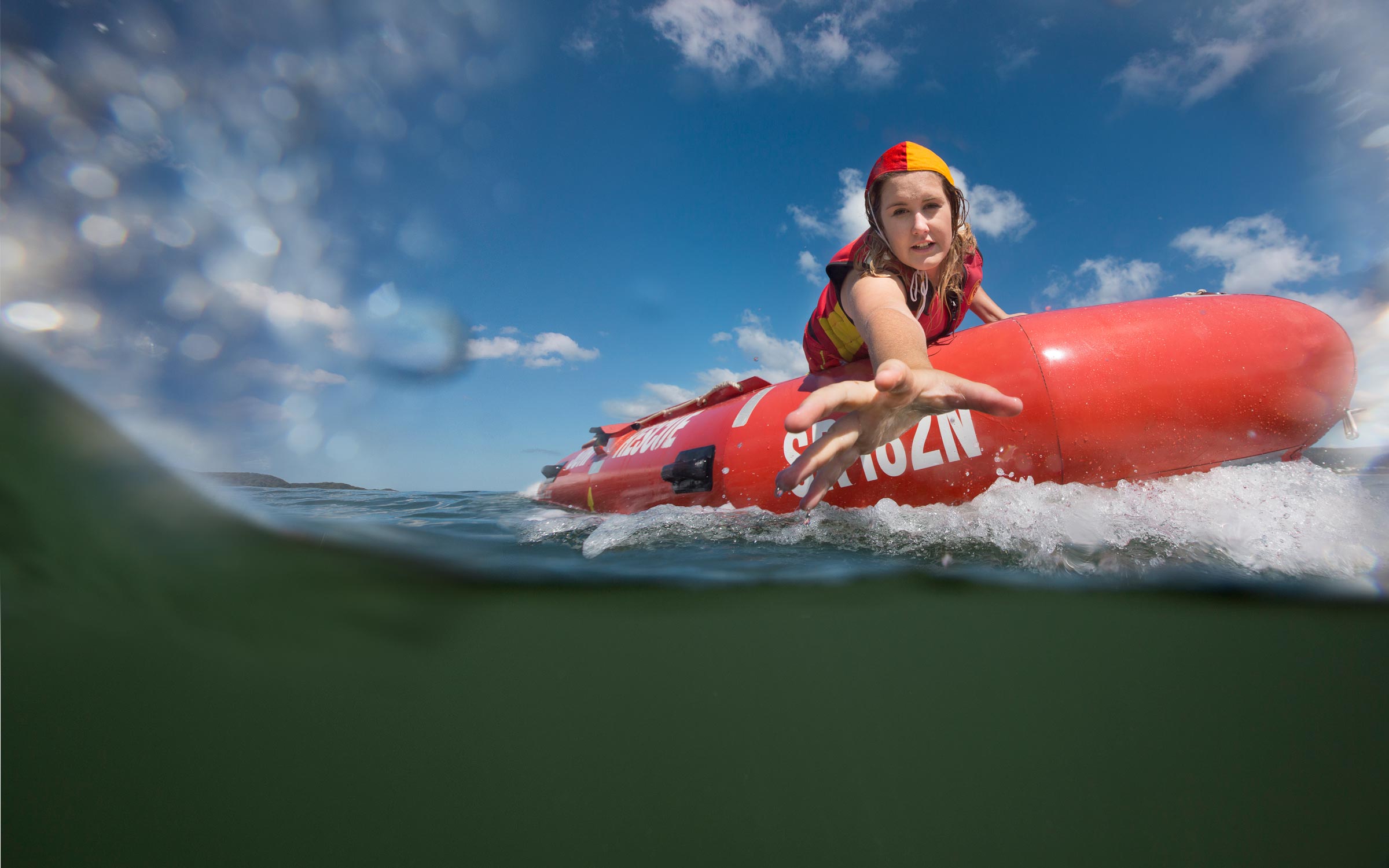 Advertising photography of female lifeguard on rescue boat reaching out to rescue victim