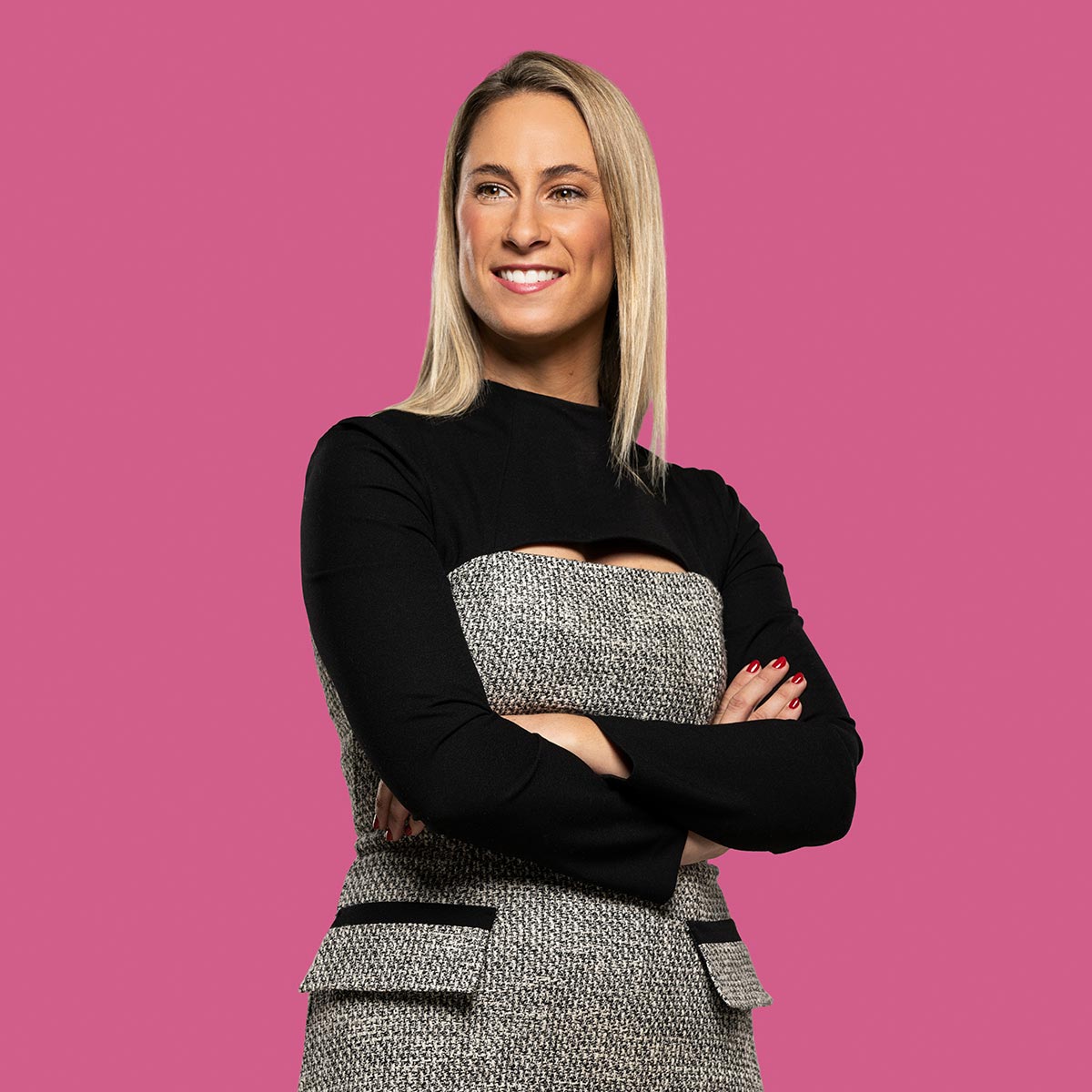Studio feature portrait of female real estate auctioneer smiling arms folded looking off camera on pink background